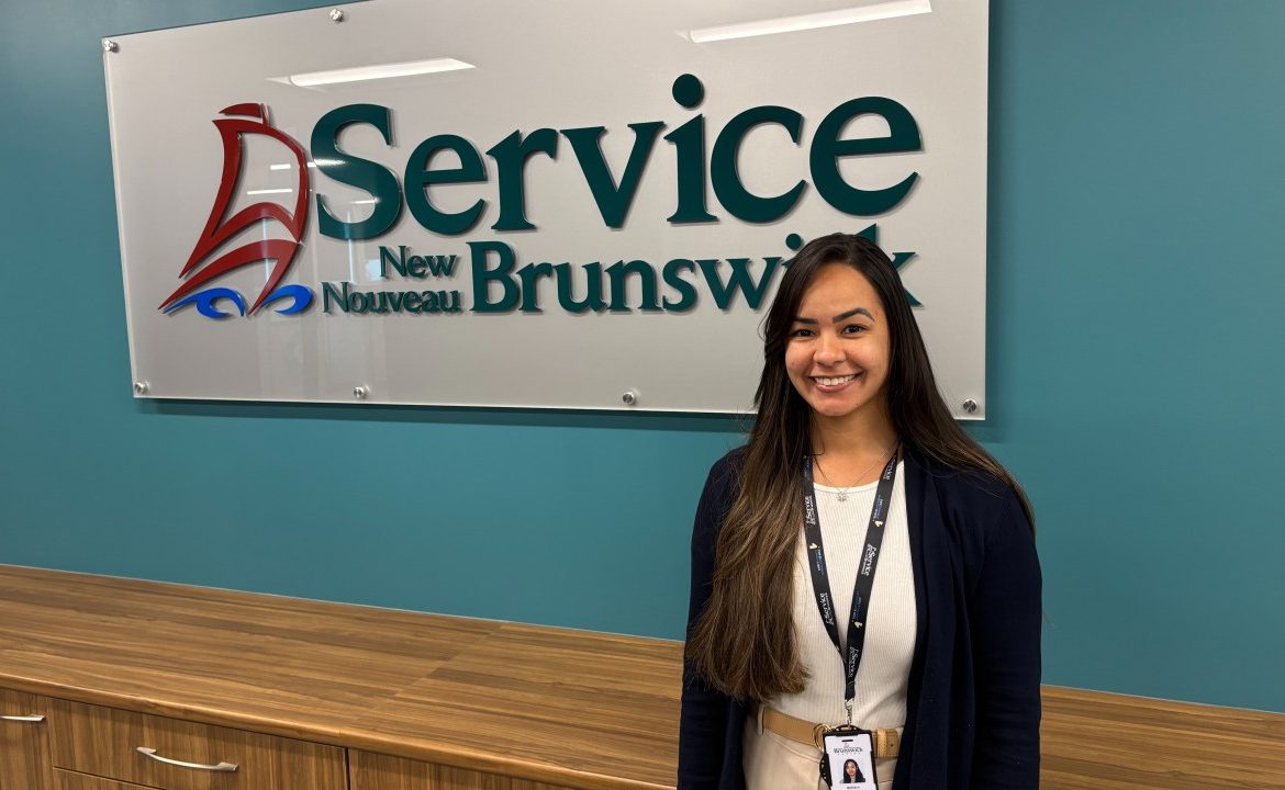 Une femme pose devant le logo de la Ligne d'écoute consacrée au traitement des dépendances et de la santé mentale au Nouveau-Brunswick